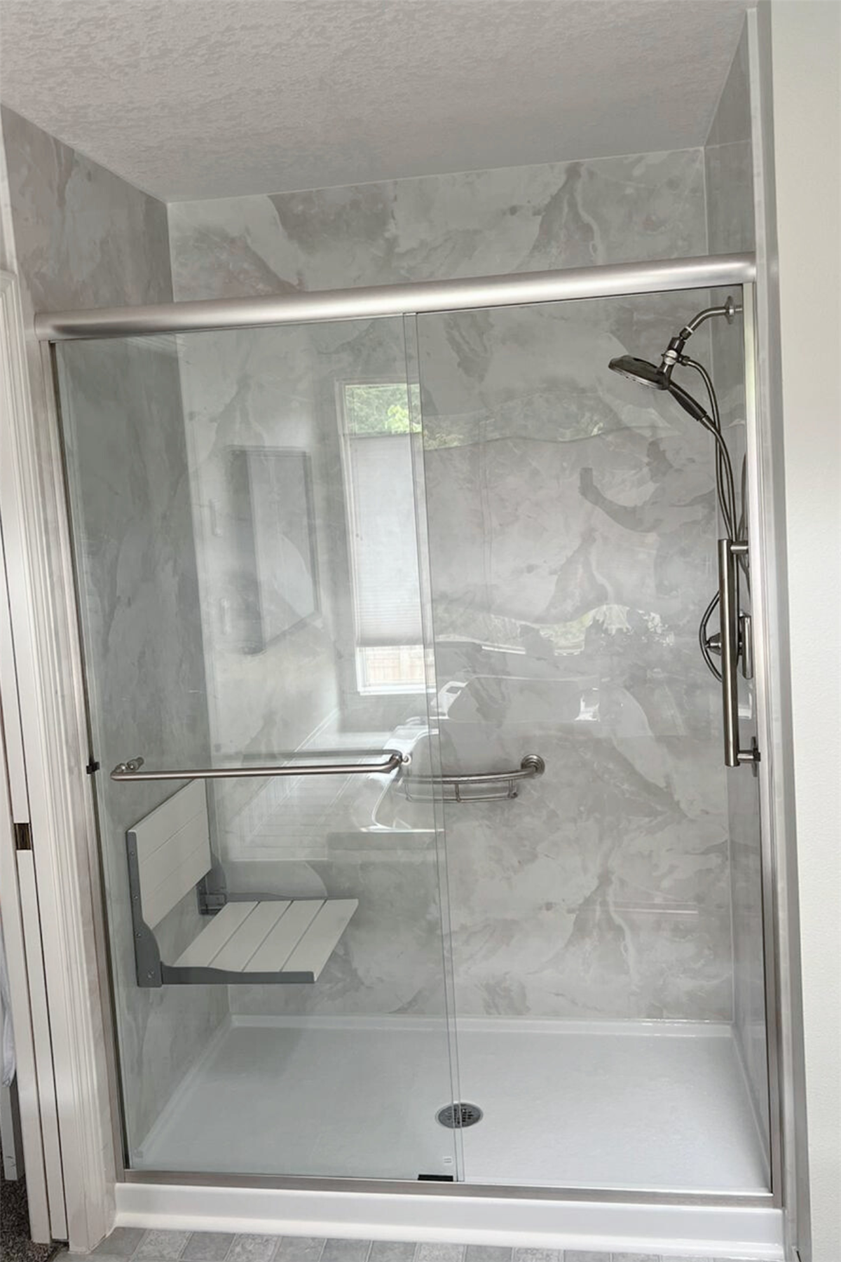 Accessible walk-in shower with glass enclosure and stainless steel grab bars