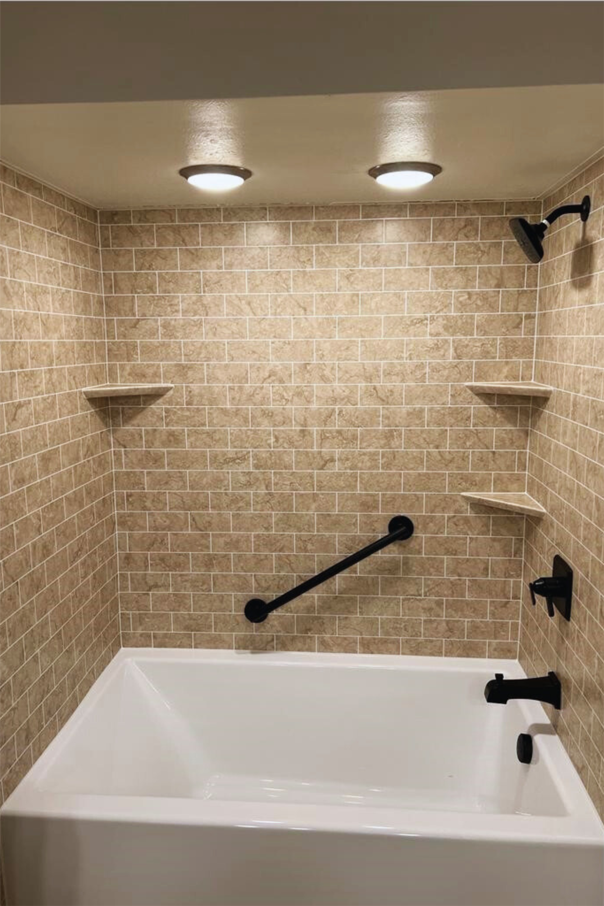Beige tile-look bath wall surround with black accessibility grab bar