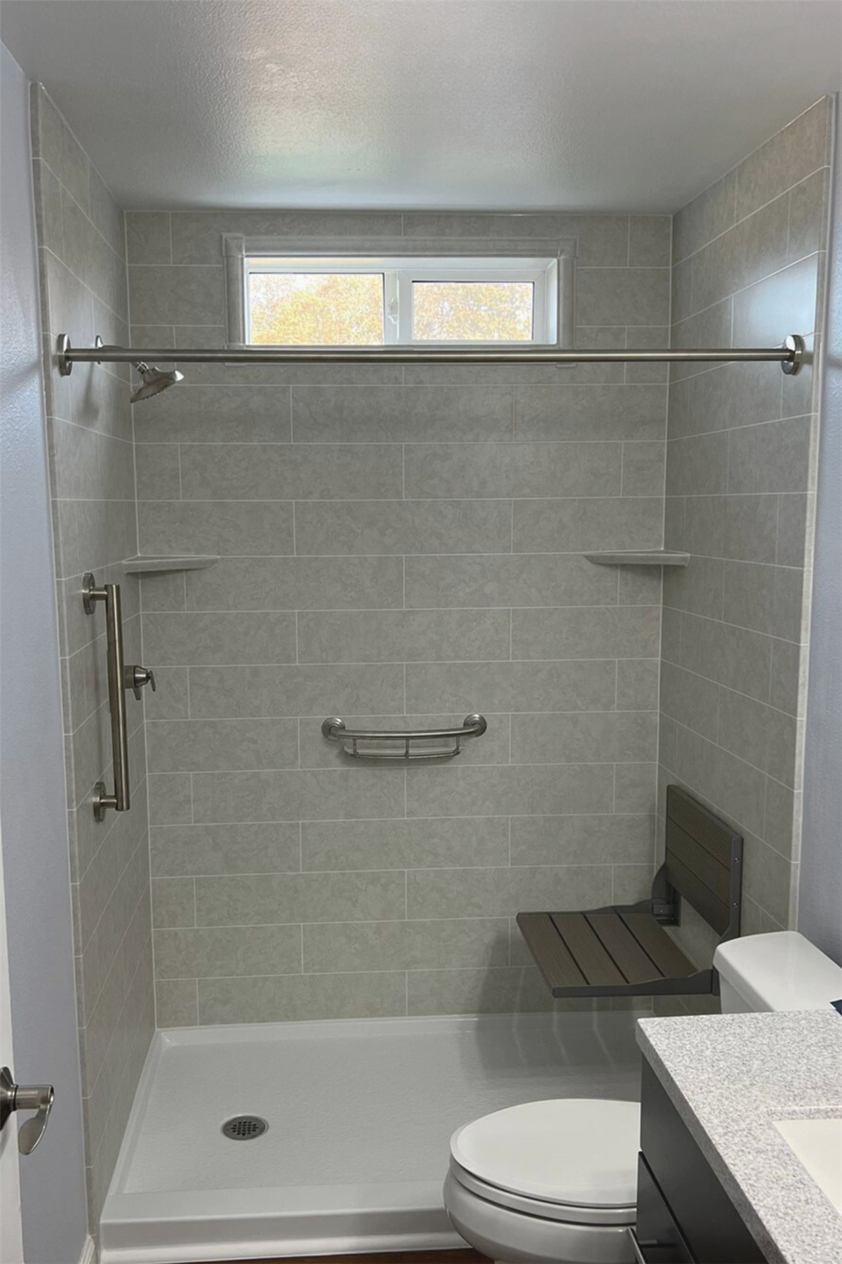 Gray tile-look shower surround with stainless steel grab bar