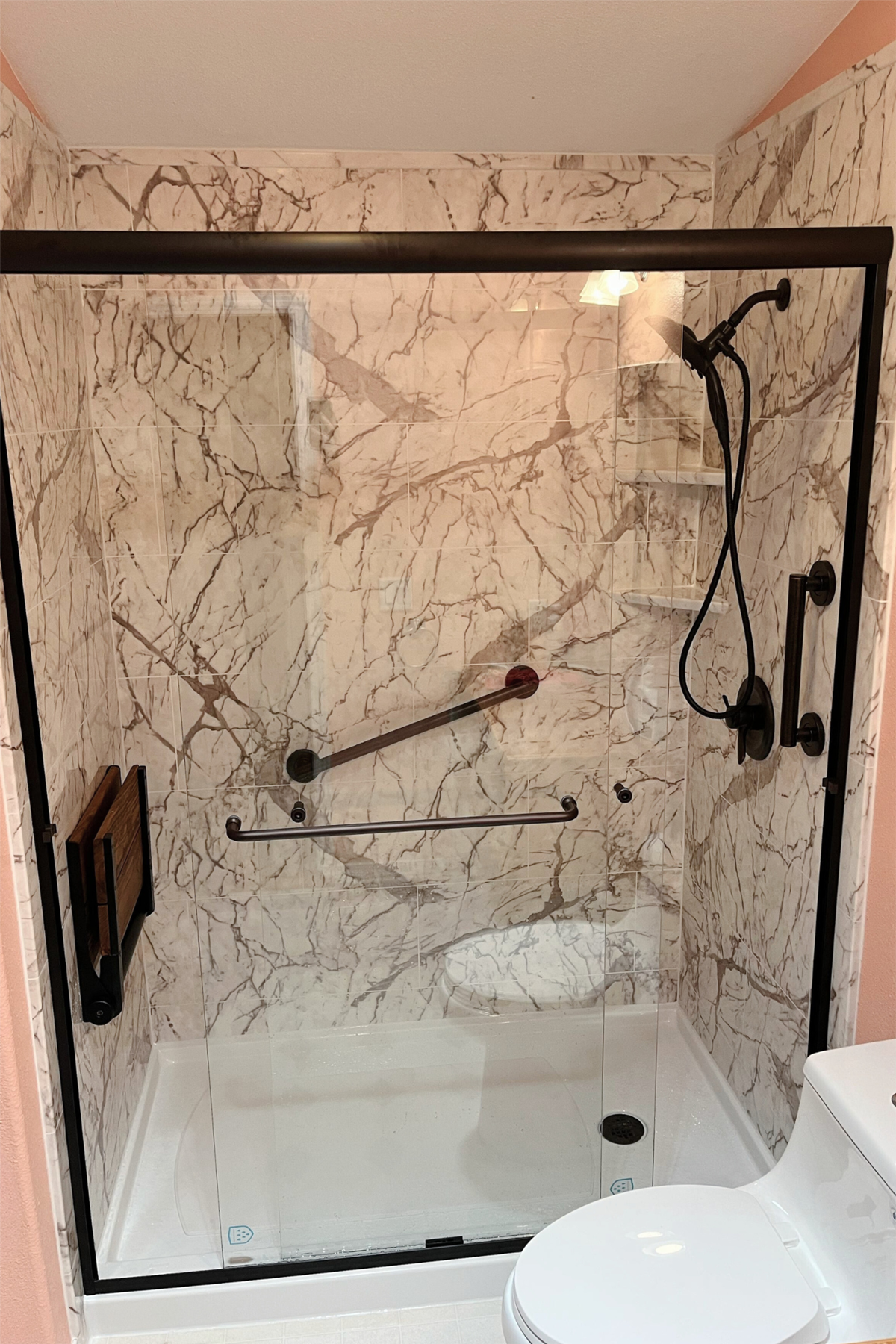 Marble-look accessible shower wall with horizontal and angled grab bars