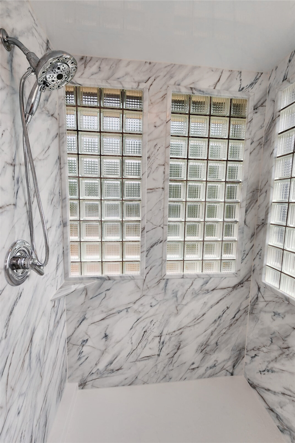 Marble-look shower surround installed around glass block windows
