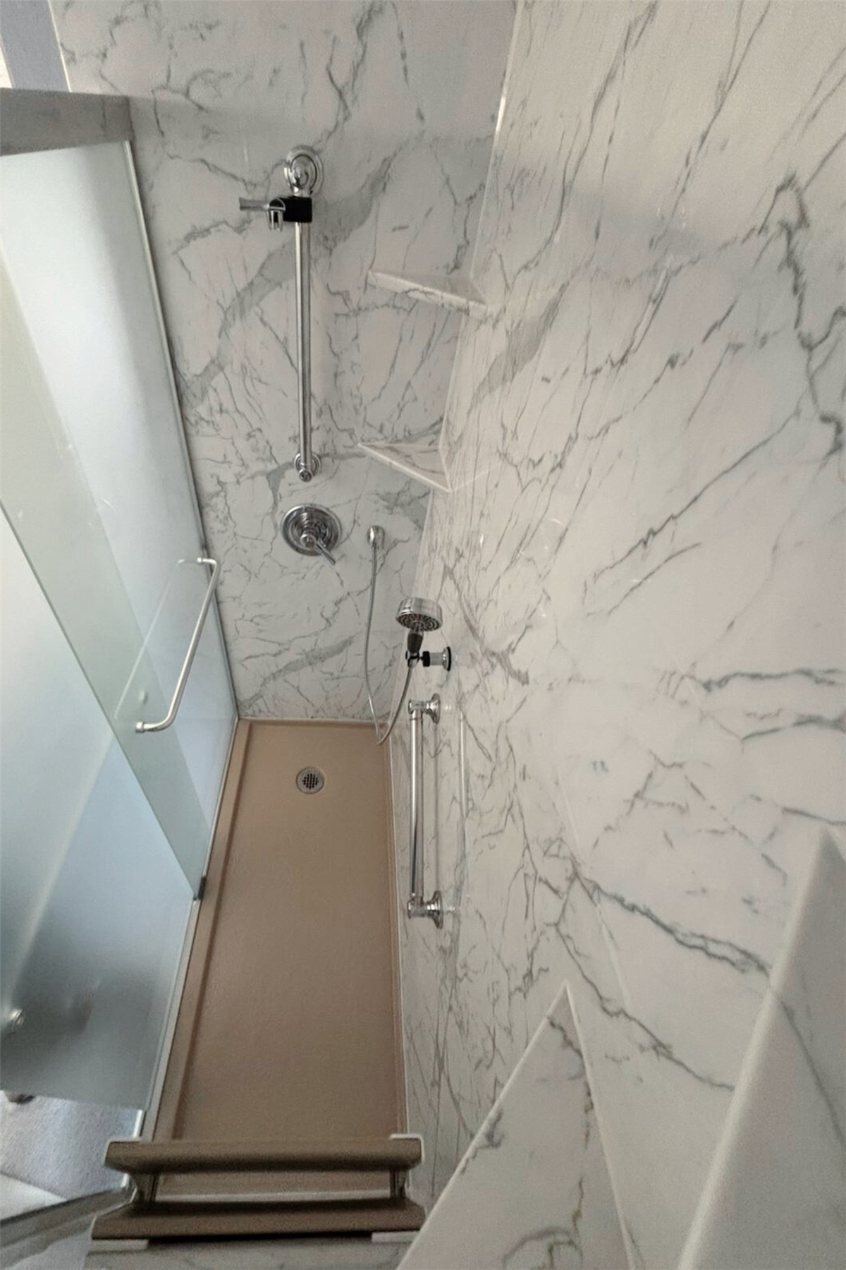 Marble-look shower surround with chrome fixtures and handheld showerhead