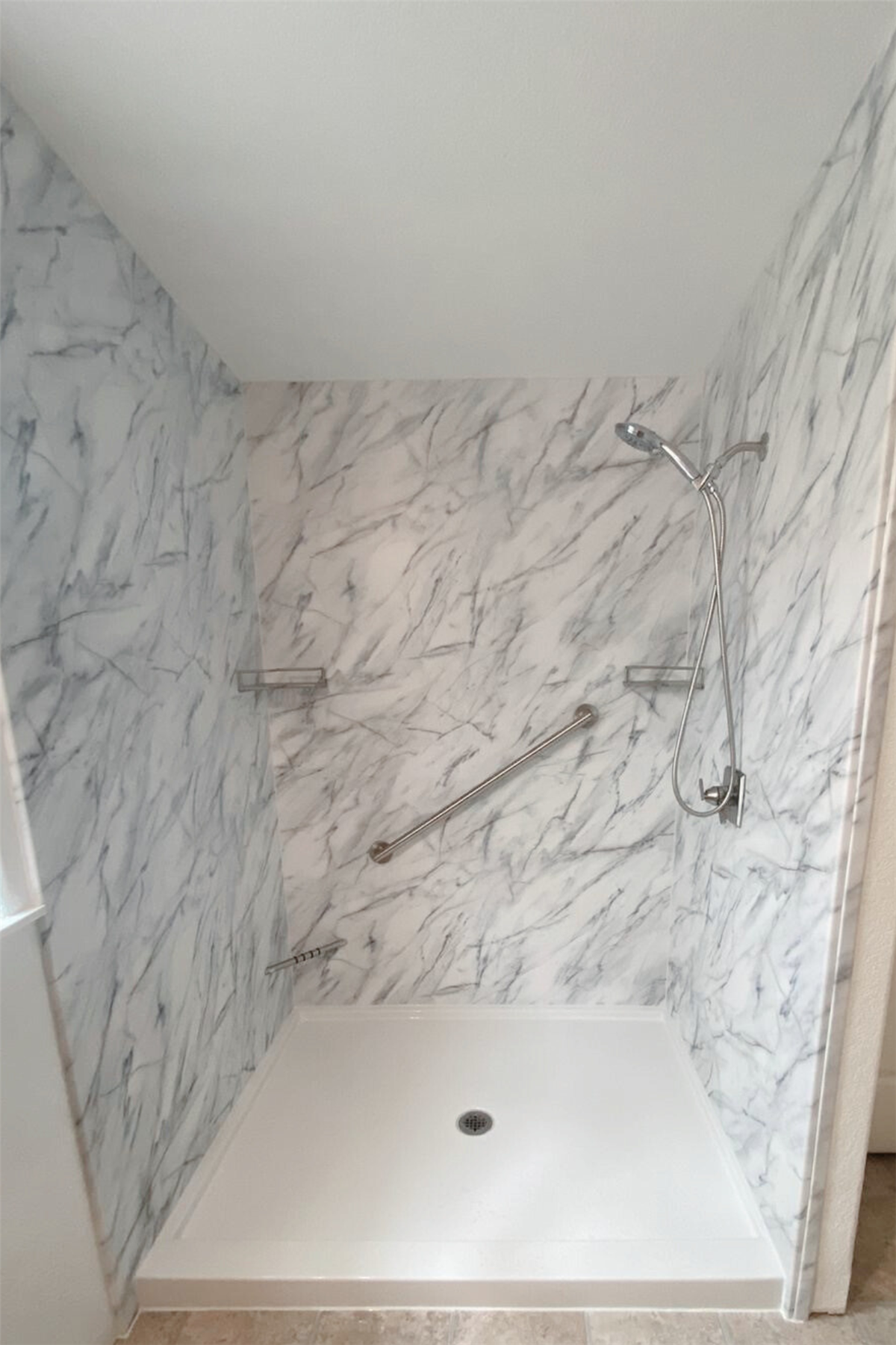 Marble-look shower surround with stainless steel safety grab bar and built-in shelves