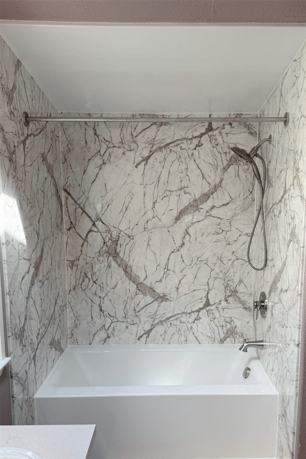 New bathtub with gray marble-look wall surround