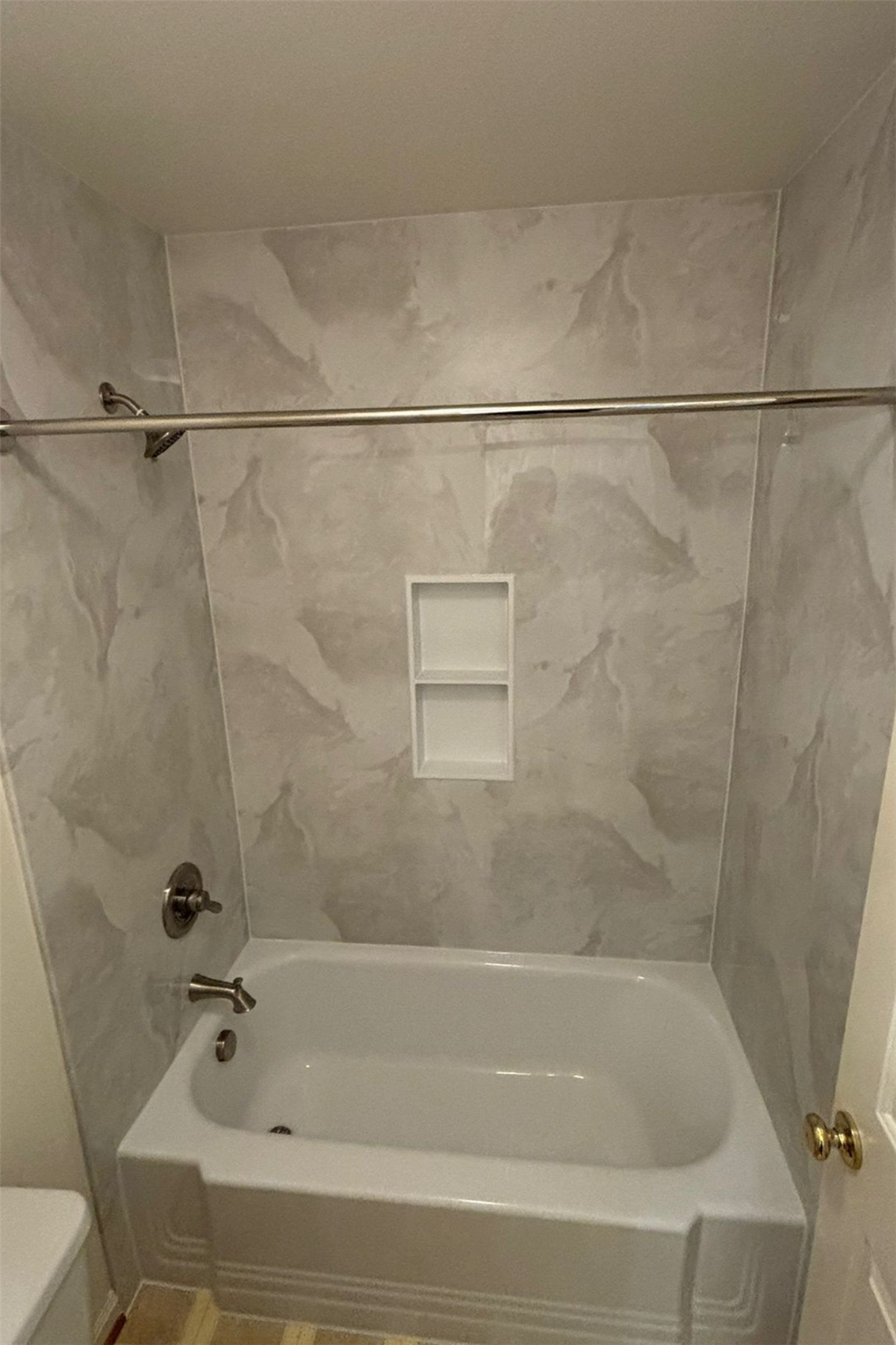 Stone-look bath wall surround with recessed two-tier storage niche
