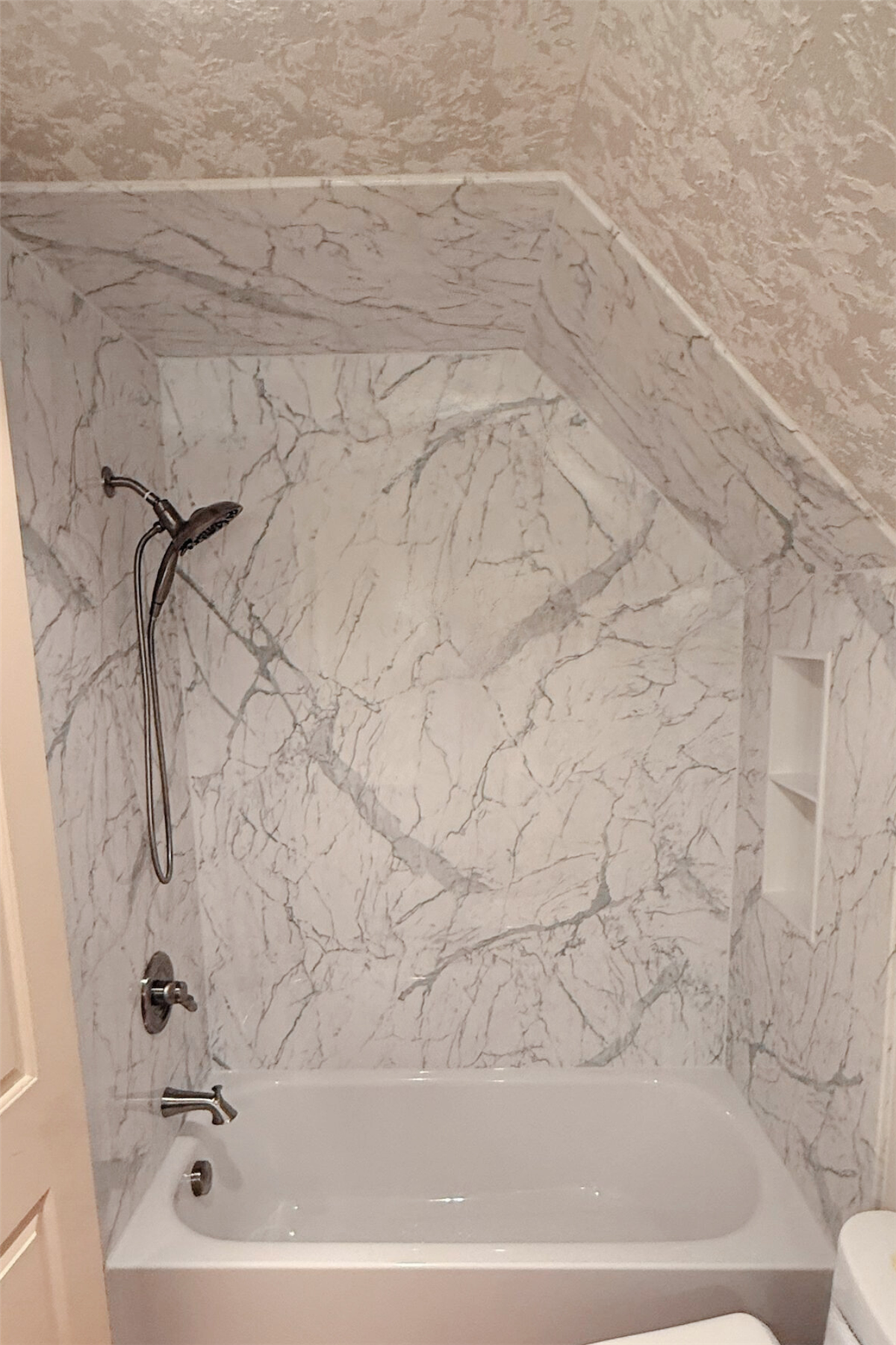 White bathtub with marble-look wall panels