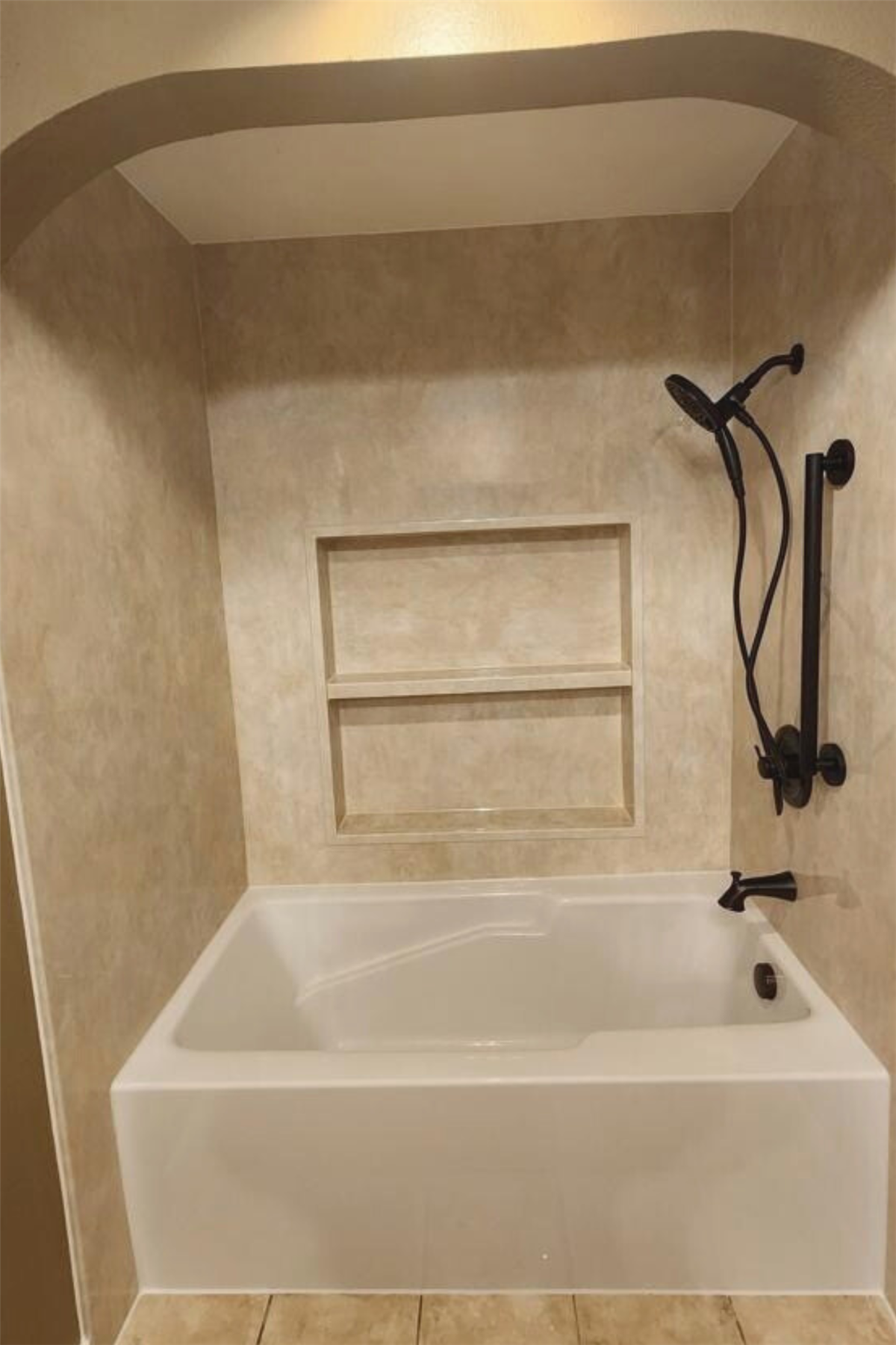 White replacement tub with stone-look wall surround and recessed storage shelves