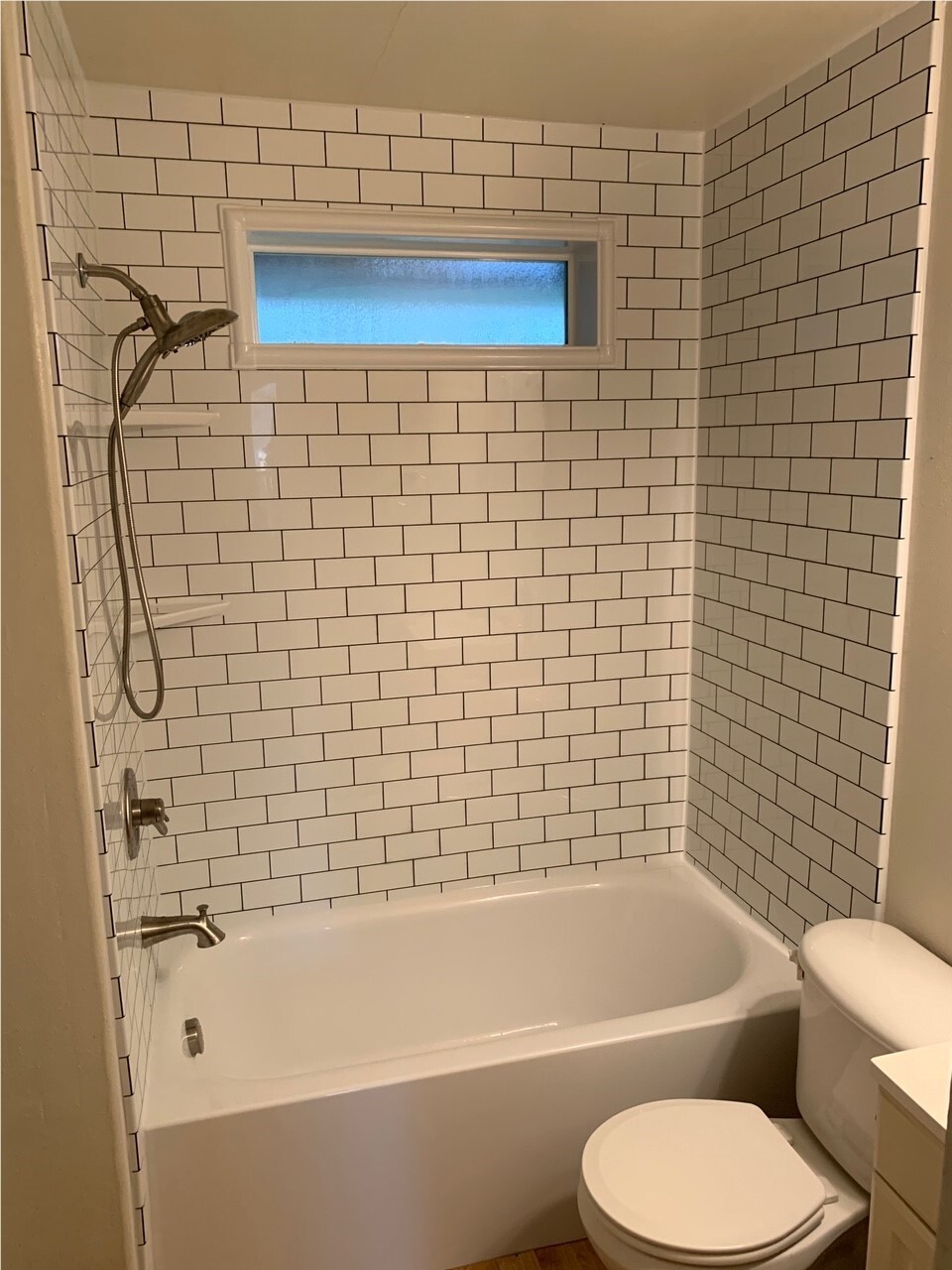 White subway tile bathtub surround with black fixtures