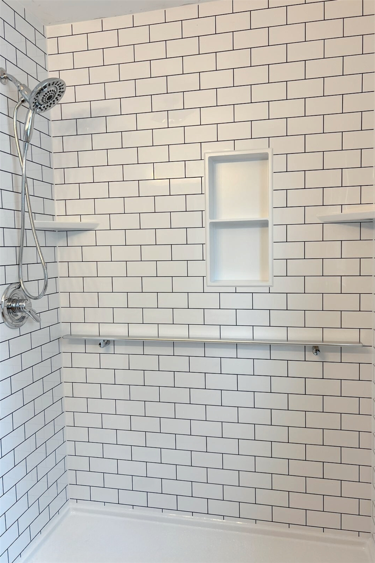 White subway tile shower surround installed around a frosted window