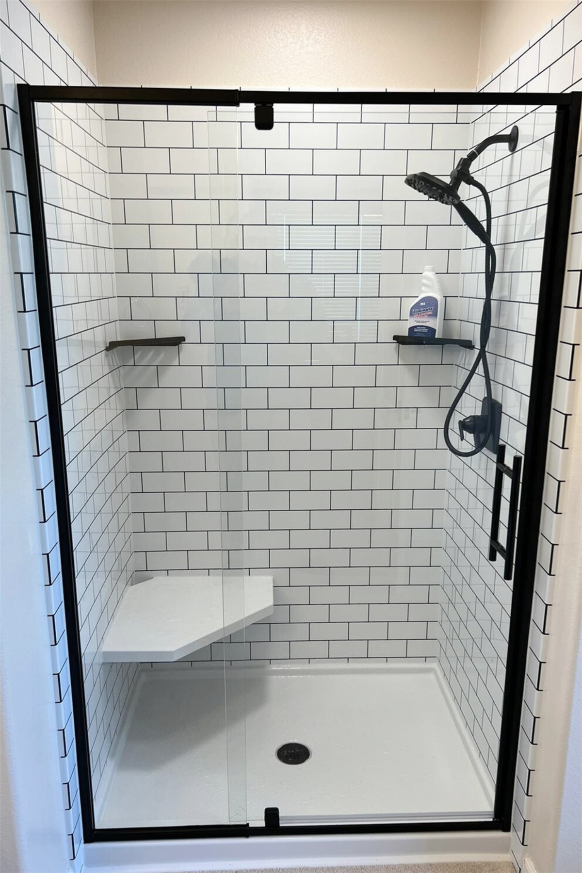 White subway tile shower with built-in shelves and accessible grab bar