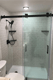 Glass-enclosed shower remodel with gray tile-look walls and black fixtures