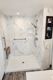 Marble-look shower surround with built-in niche, grab bar, and chrome fixtures
