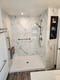 Marble-look shower with recessed storage niche, handheld showerhead, and stainless steel grab bar