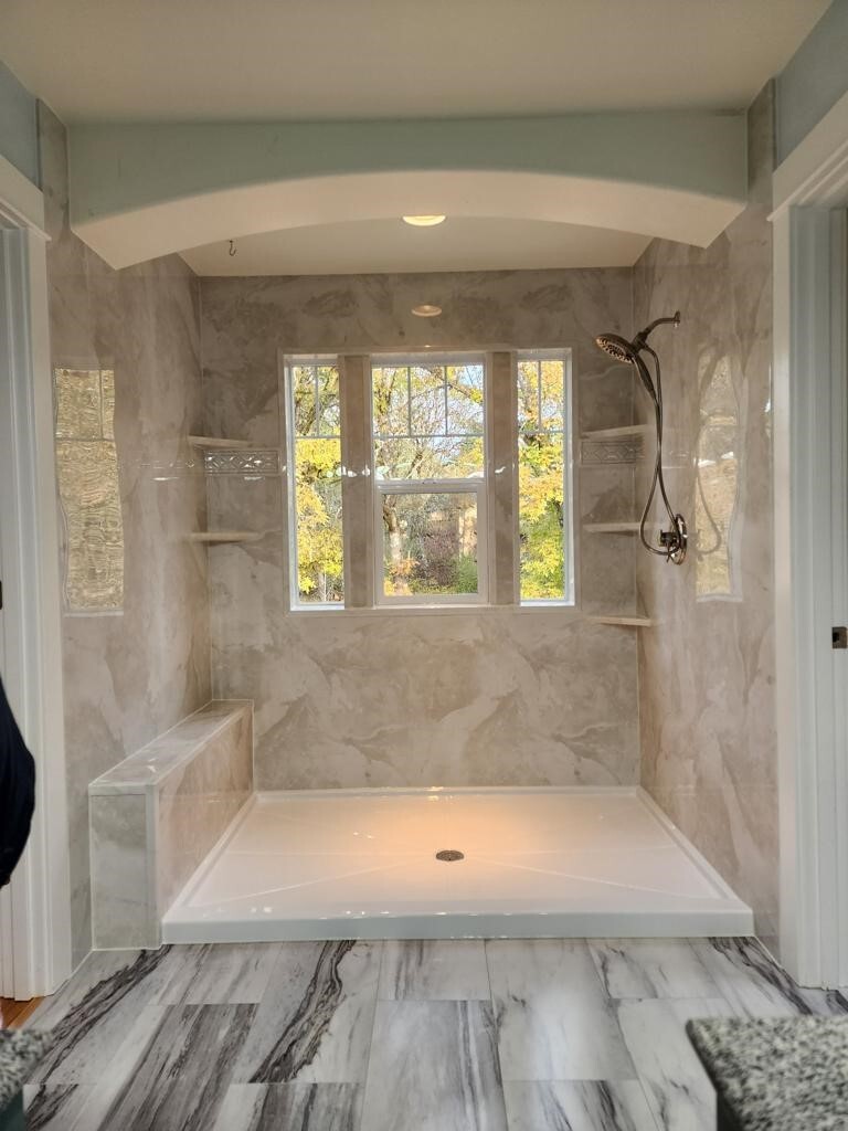 Marble-look walk-in shower with large window and built-in corner shelves
