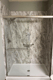 Marble-look walk-in shower with stainless steel grab bars and built-in shelf