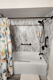 New bathtub with marble-look wall surround and black grab bar