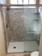 Remodeled walk-in shower with gray marble-look walls and stainless steel grab bar
