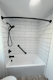 Replacement bathtub with white subway tile surround and black safety grab bar