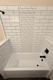 Replacement bathtub with white subway tile walls and decorative accent pattern