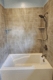 Shower-to-tub conversion with gray tile-look walls and built-in corner shelves