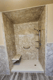 Stone-look shower surround with built-in corner shelves and grab bar