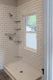 Walk-in shower with white subway tile walls and frosted bathroom window