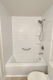White bathtub with subway tile surround and stainless steel grab bar