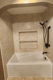 White replacement tub with stone-look wall surround and recessed storage shelves