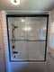 White subway tile shower with recessed niche, handheld showerhead, and black grab bars
