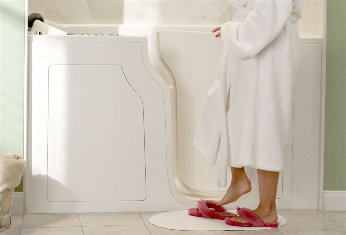 Person in a robe standing beside a walk-in tub